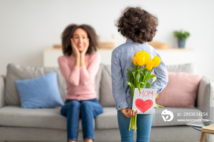 Black girl greeting mom with tulips and card