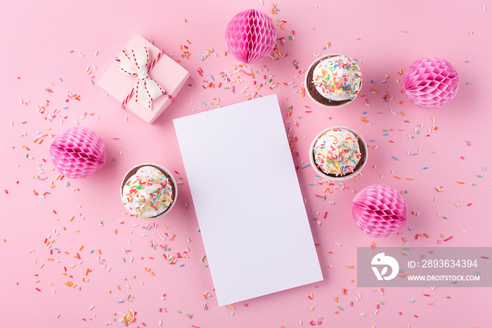 空的白色空白、礼盒、纸装饰品和粉红色背景的纸杯蛋糕。