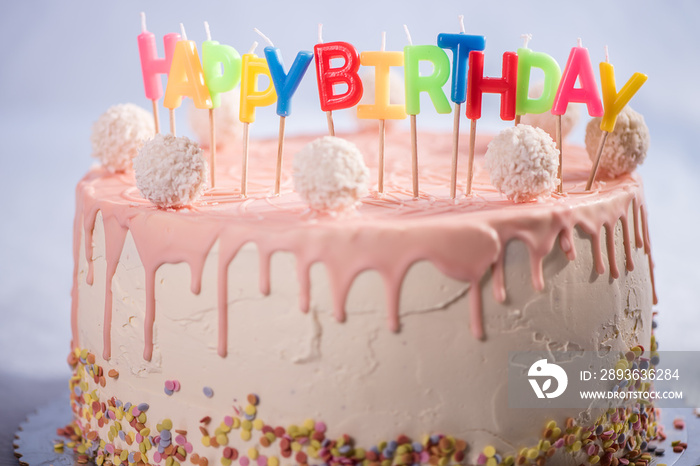 粉白色蛋糕配椰子球和生日快乐蜡烛