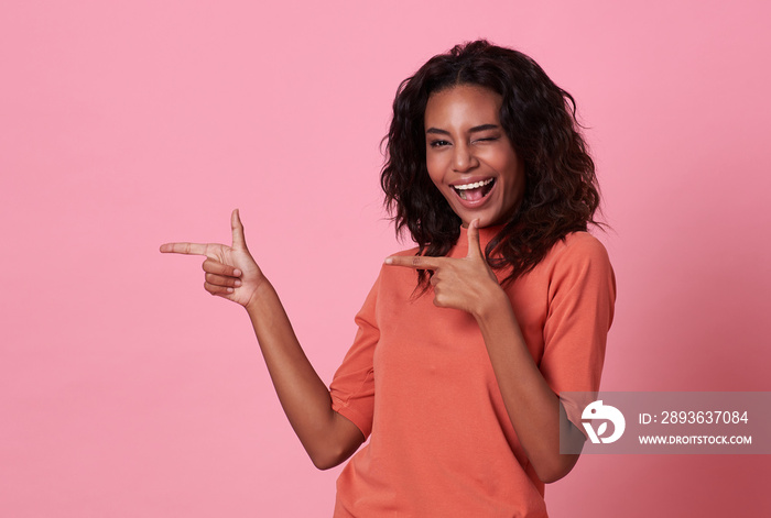 Happy young african woman standing with her finger pointing isolated over pink banner background wit