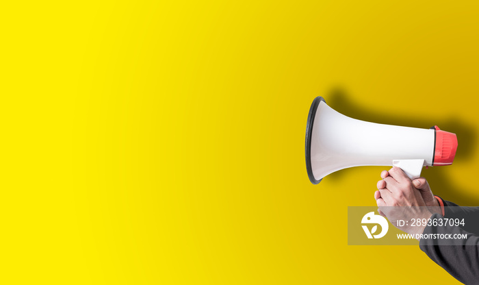 holding megaphone with both hands against yellow background template