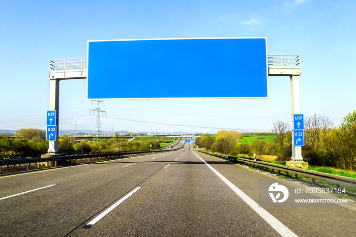 Blank blue freeway sign over the road on sunny day