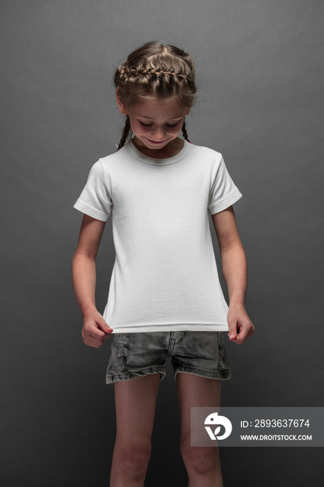 穿着白色t恤的小女孩，灰色背景上有你的标志或设计空间