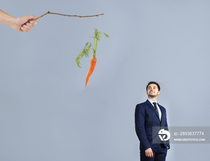 Motivation and goal concept. Young man looking at carrot, color background