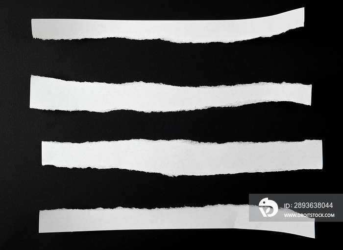 torn blank white paper strips against a black background