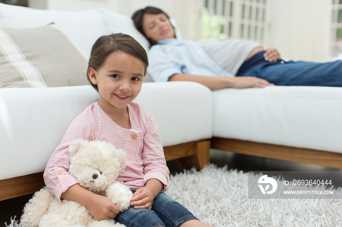 Portrait cute girl with teddy bear by pregnant mother sleeping on sofa