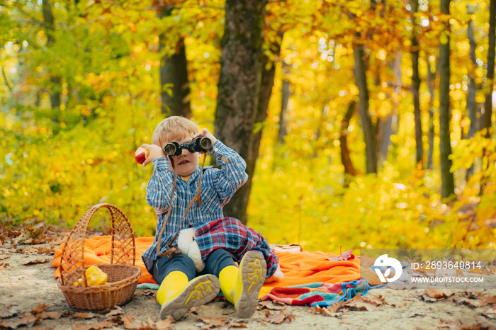 Boy in rubber boots relaxing in forest sit picnic blanket. Cute tourist concept. He likes hiking. Ki