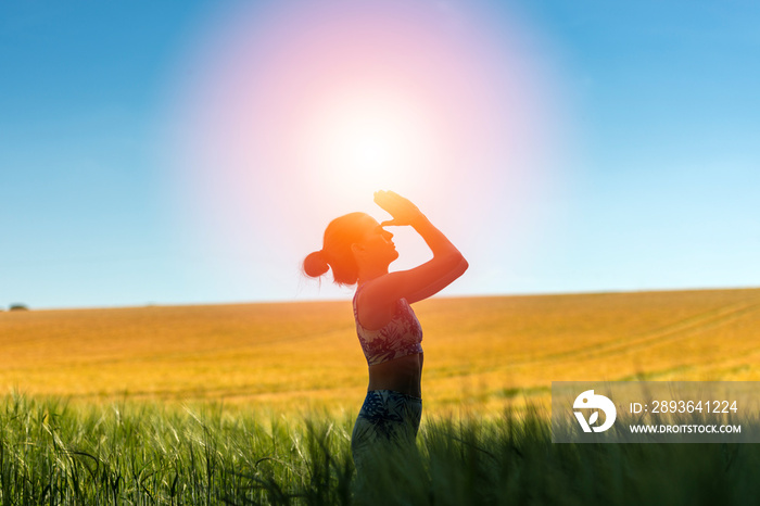 woman standing in a field meditating, yoga pose.