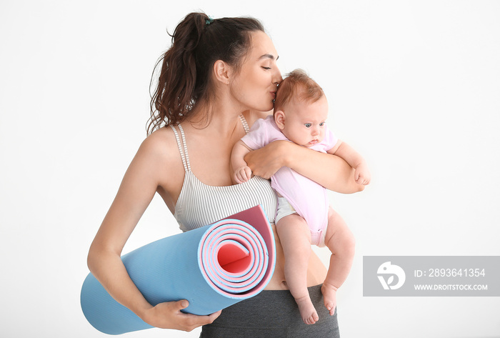 Mother with yoga mat and cute little baby on white background