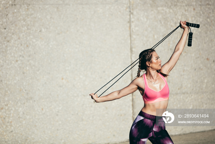 Strong woman in stretching with skipping rope