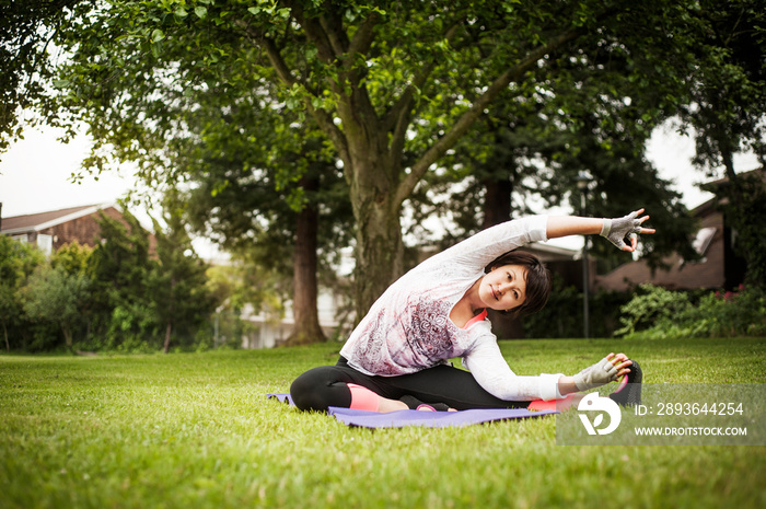 Portrait of woman practicing yoga on grassy field