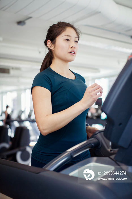 Confident female athlete running on treadmill in gym