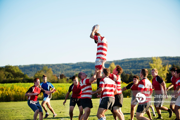 Rugby player jumping to catch ball in lineout supported by teammates