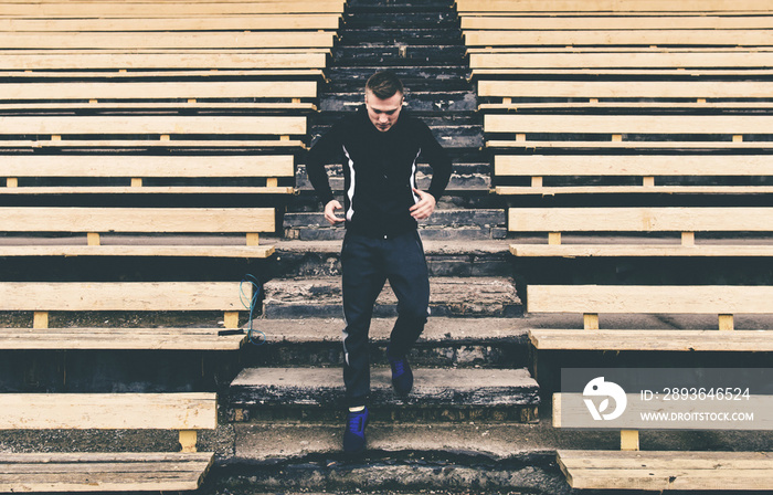 Young man runner running the stairs in the stadium