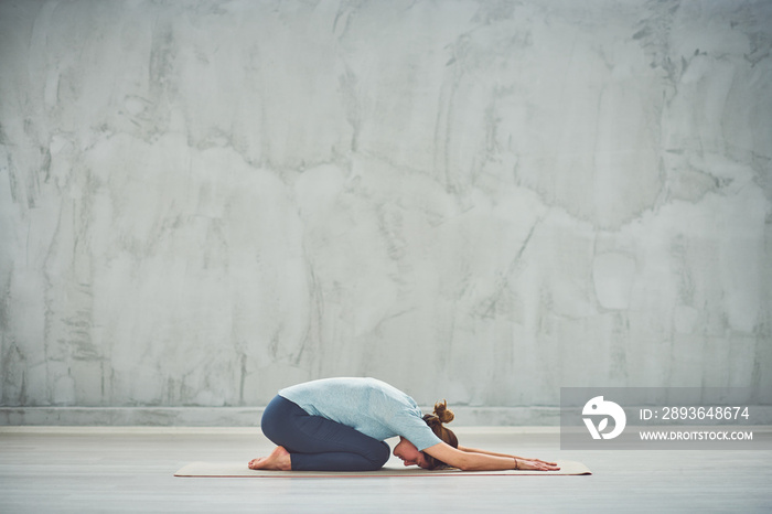 Fit Caucasian brunette doing Extended Childs yoga exercise.