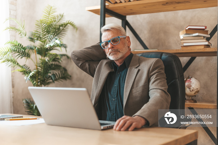 Pain in the neck. Mature man in the office at the table, migraine discomfort. Workplace stress.