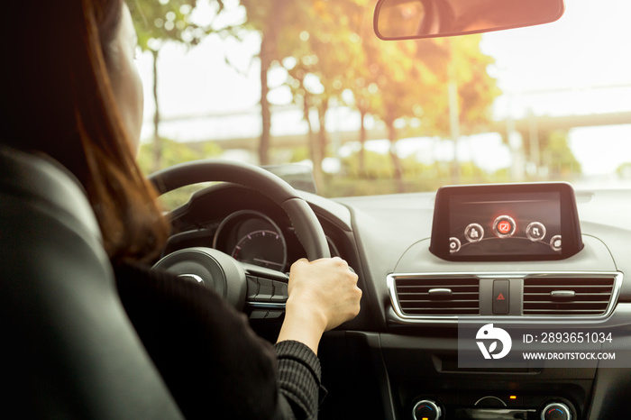 Woman driving her modern car on country road in sunlight.