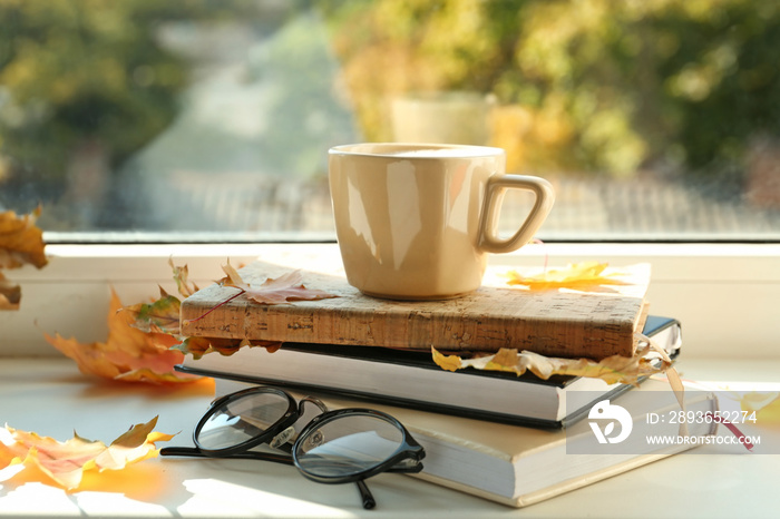 一杯热咖啡，窗台上放着书和秋叶