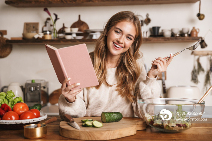 快乐可爱的女人一边做晚饭一边看笔记本的画面