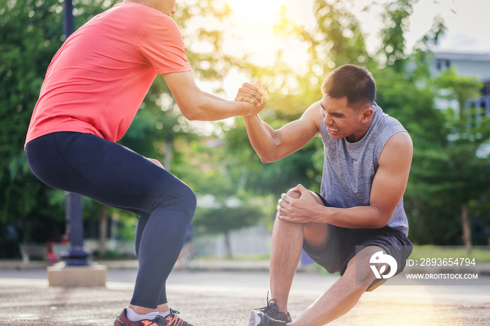 Running man helping hand to his friend by knee injury in running practice