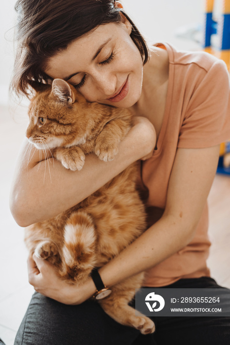 微笑的女人拥抱她的猫。特写肖像。女人在室内拥抱猫，非常适合任何p