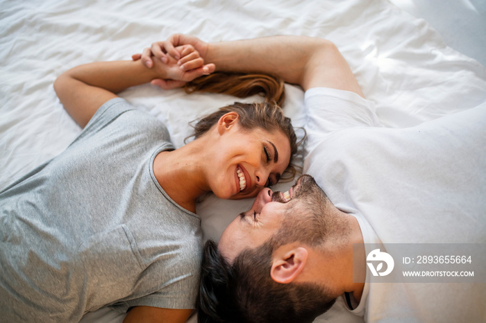 Pretty female looking at her boyfriend in bed stock photo. Overhead close up of young couple lying i