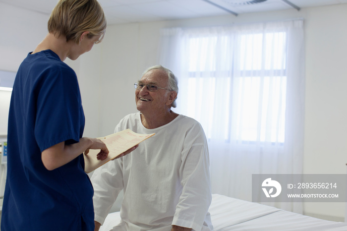 Happy senior patient talking with nurse in hospital room