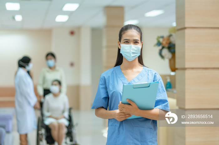 Asian female doctor wearing face mask working in hospital with patient sitting on wheelchair backgro