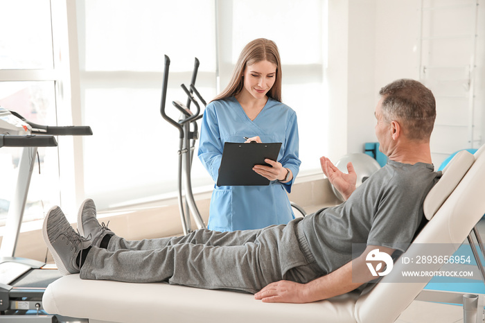 Physiotherapist working with mature patient in rehabilitation center