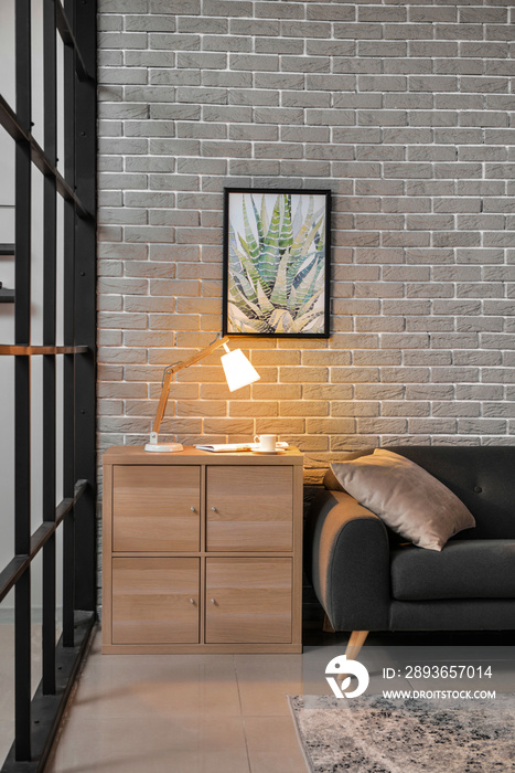 Chest of drawers with glowing lamp in interior of living room