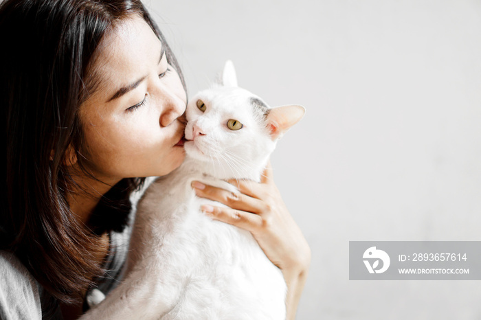 Asian woman kissing cute white cat closeup