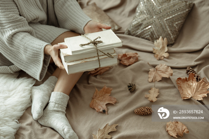 Stack of books in female hands, autumn background, copy space.