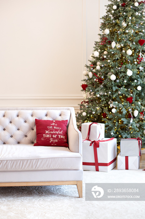 豪华客厅内部配有沙发装饰的别致圣诞树、礼物和枕头。经典内饰