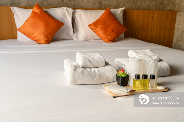 Set of hotel amenities (such as towels, shampoo, soap, drinking glass etc) on the bed. Hotel ameniti