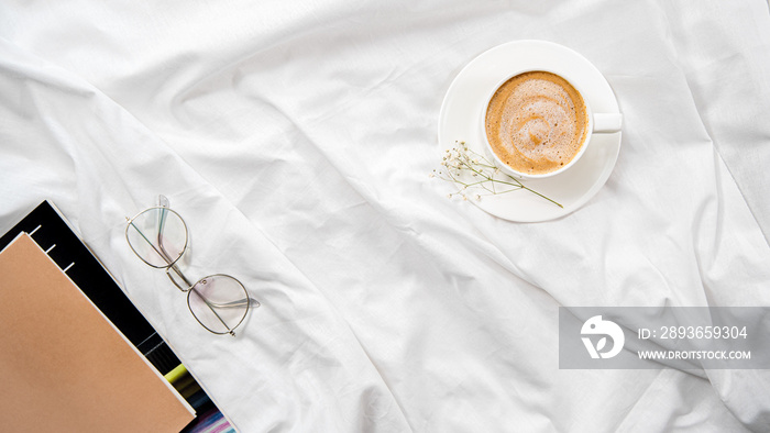 Morning flatlay in white bed. Coffee and morning routine. Read in bed. Copy space. Concept minimalis