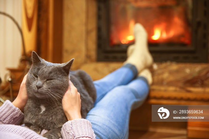 一个女人带着一只可爱的猫在家里的壁炉旁休息
