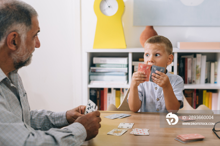 boy playing cards with his grandfather at home