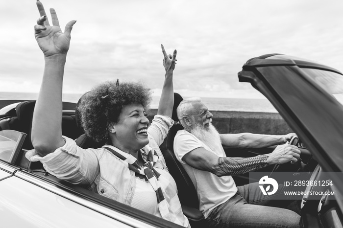 Happy senior couple having fun in convertible car during summer vacation - Focus on mature woman fac