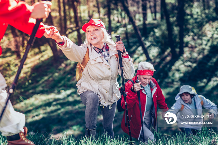 Retired woman taking hand of son while hiking all together