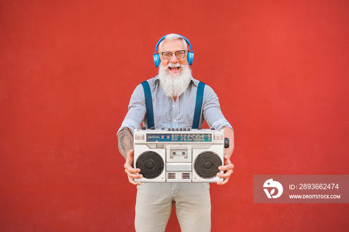 Happy senior man with boombox stereo playing music - Trendy mature guy having fun listening with vin