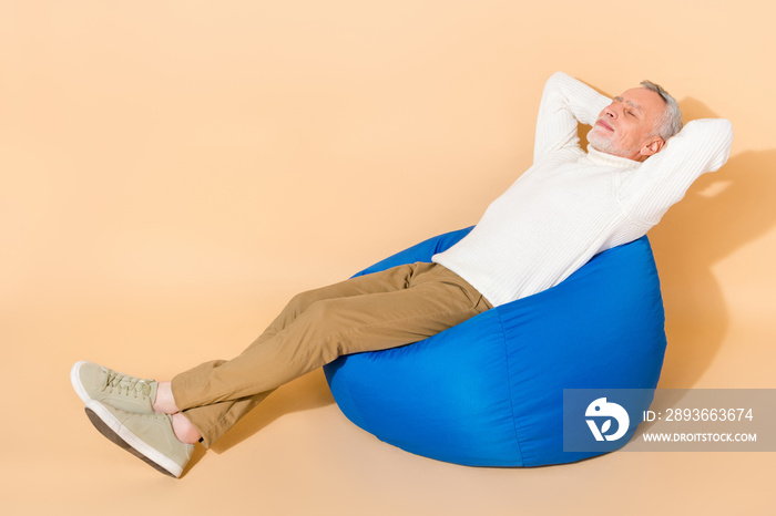 Portrait of attractive dreamy calm man lying in chair resting sleeping isolated over beige pastel co