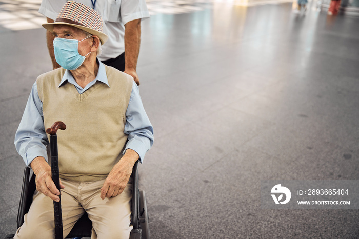 Disabled person in a transport chair staring away