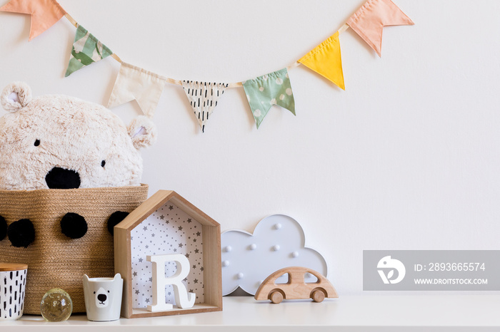 时尚的斯堪的纳维亚儿童房，白墙上挂着棉花彩旗，盒子，泰迪熊