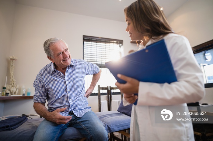 Senior male patient showing back ache to female therapist with