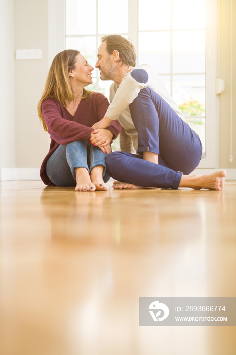 Beautiful romantic couple sitting together on the floor kissing in love at home