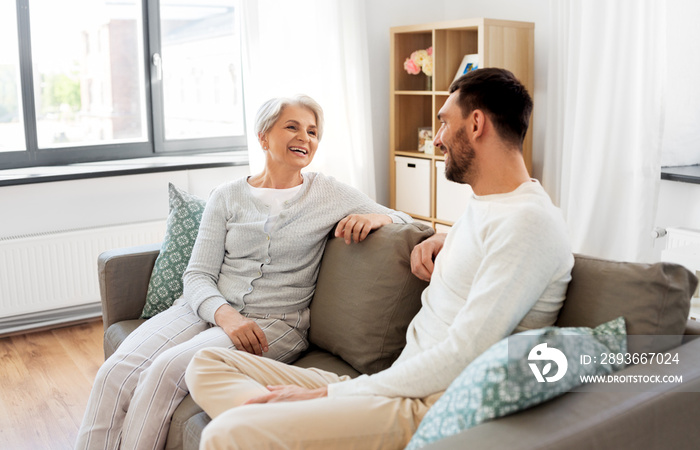 family, generation and people concept - happy smiling senior mother talking to adult son at home