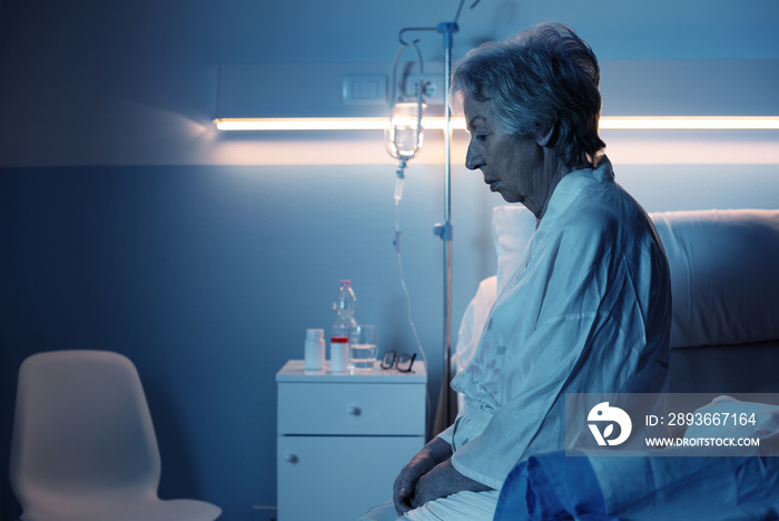 Lonely senior patient sitting on the hospital bed at night