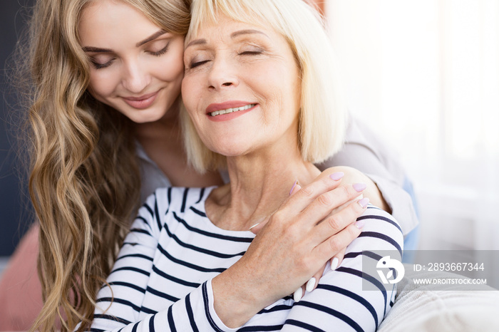 Cute young daughter embracing her mother with love