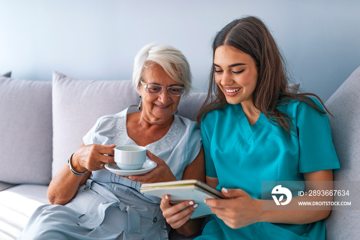 Friendly relationship between smiling caregiver in uniform and happy elderly woman