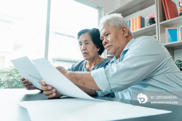 亚洲老年夫妇使用家中桌上的计算器和文书计算费用和收入